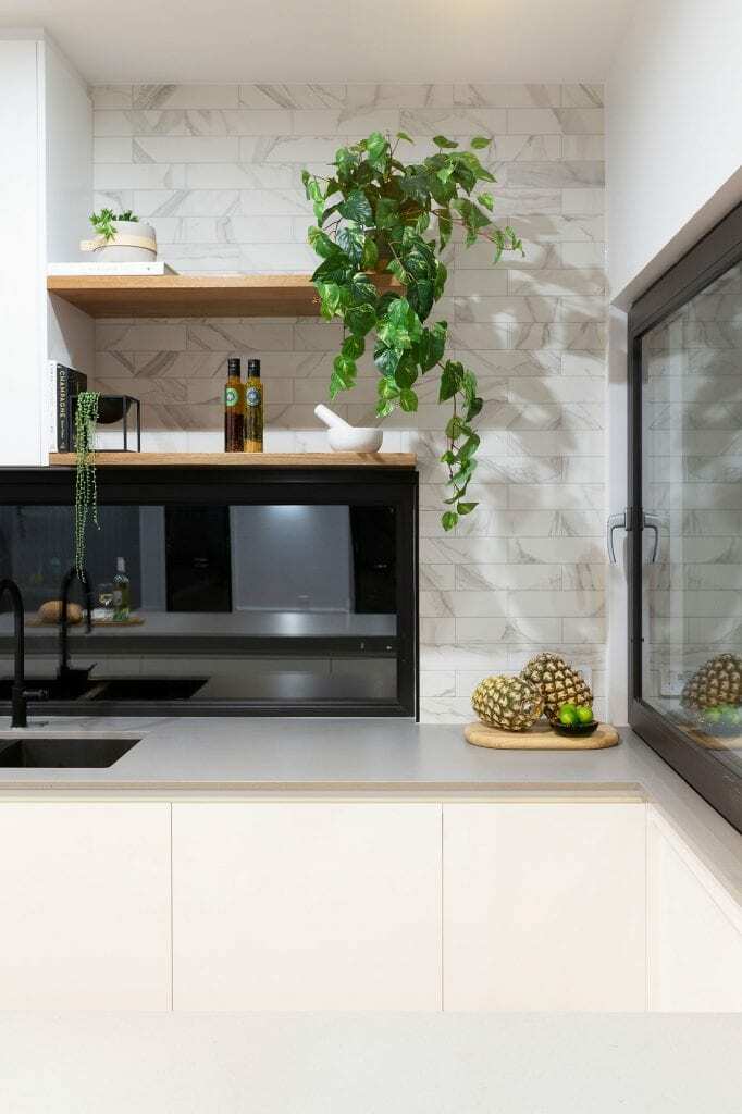 Homes by Howe, new build, Denman, kitchen, sink with white cabinetry and grey benchtop, low window behind sink, decorative pineapples and plants n