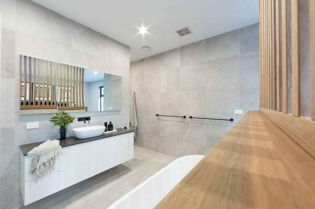 Homes by Howe, knock down rebuild, Deakin, ensuite, light gray tiling, wooden vanity and freestanding bath