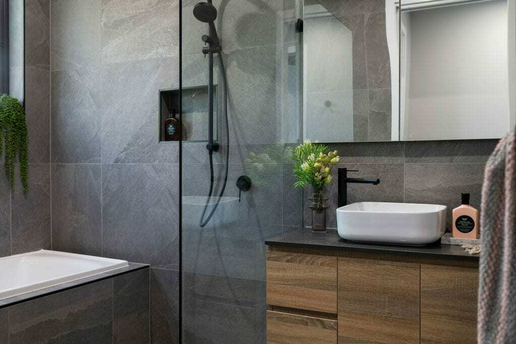 Homes by Howe, knock down rebuild, Deakin, bathroom, grey slate tiling, glass shower door, wooden vanity and mirror