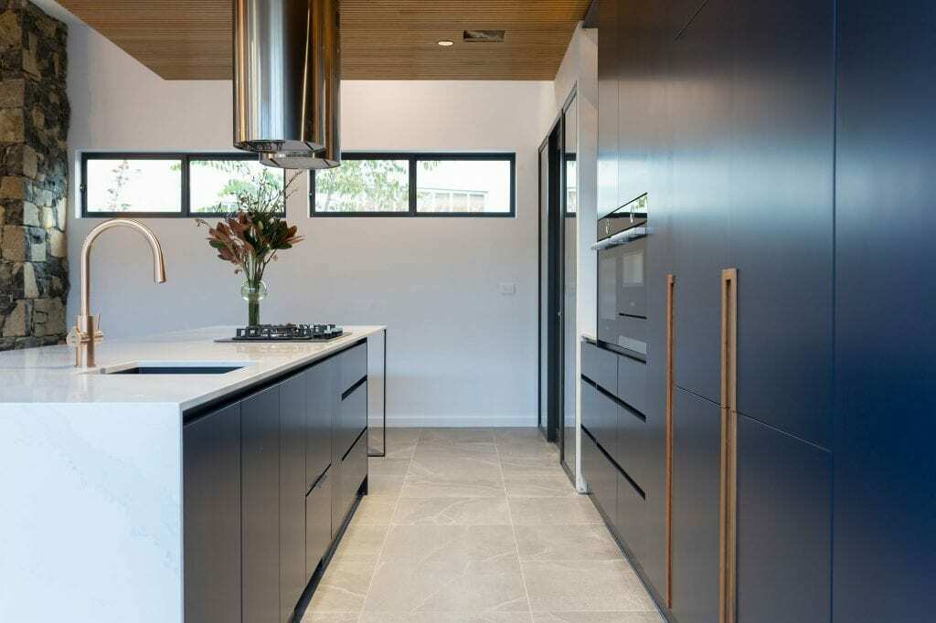Homes by Howe, knock down rebuild, Deakin, kitchen, navy blue cabinetry with white talostone benchtops and gold facets, large central island with slatted wood detailing on ceiling above