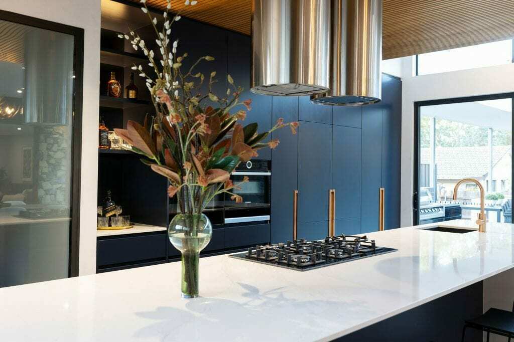 Homes by Howe, knock down rebuild, Deakin, kitchen, navy blue cabinetry with white talostone benchtops and gold facets, large central island with slatted wood detailing on ceiling above