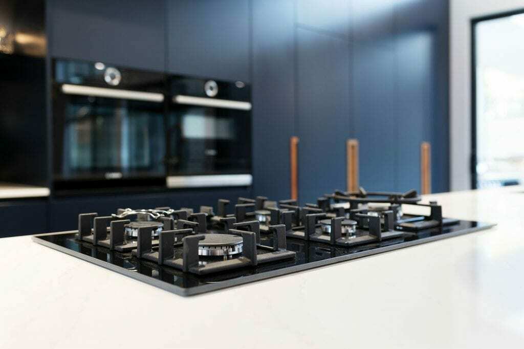 Homes by Howe, knock down rebuild, Deakin, kitchen, navy blue cabinetry with white talostone benchtops and gold facets, large central island with slatted wood detailing on ceiling above