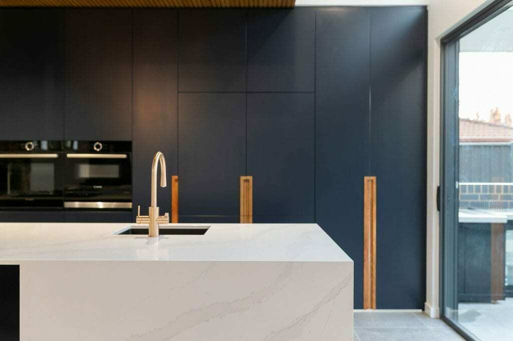 Homes by Howe, knock down rebuild, Deakin, kitchen, navy blue cabinetry with white talostone benchtops and gold facets, large central island with slatted wood detailing on ceiling above