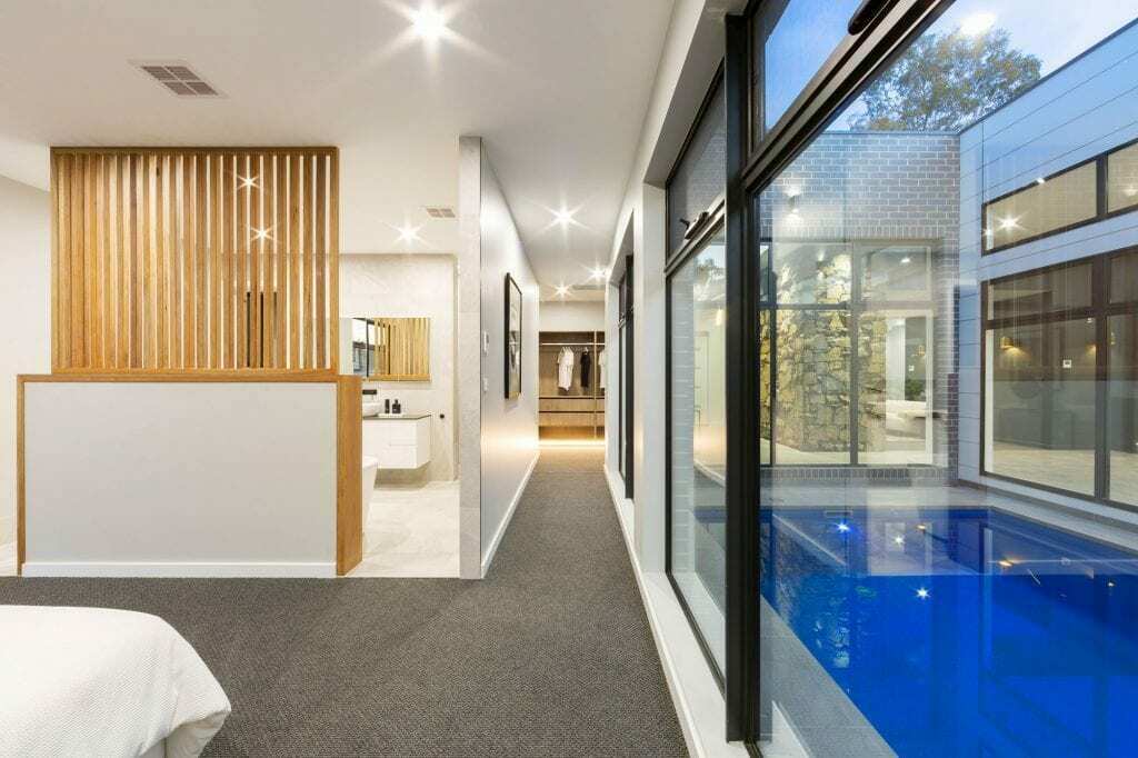 Homes by Howe, knock down rebuild, Deakin, master bedroom with attached ensuite and view out onto courtyard pool, large floor to ceiling windows
