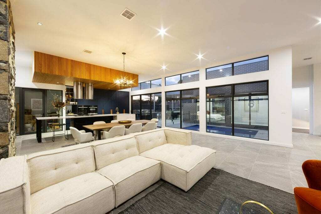 Homes by Howe, knock down rebuild, Deakin, open plan living area looking out onto courtyard pool, drystone wall fireplace
