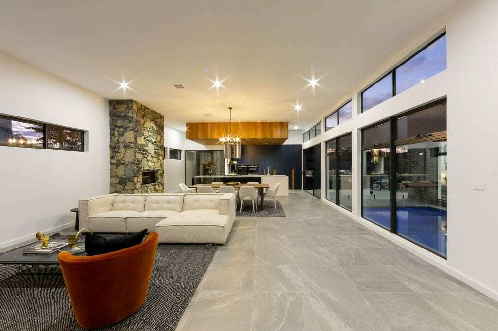 Homes by Howe, knock down rebuild, Deakin, open plan living area looking out onto courtyard pool, drystone wall fireplace