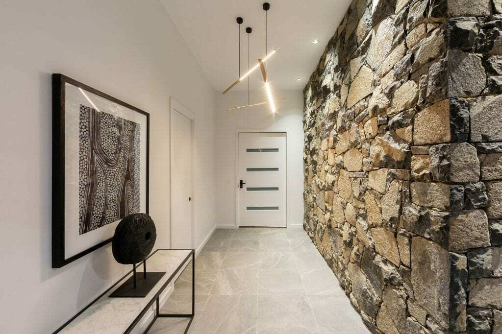 Homes by Howe, knock down rebuild, Deakin, hallway, dry stone wall on right looking down to front door, white wall and painting on left, grey tiling