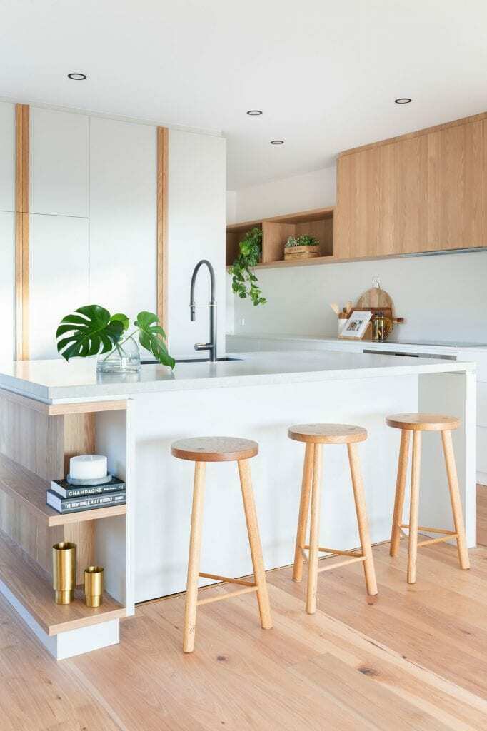 Homes by Howe, new build, Denman, kitchen, light wooden flooring, 3 bar stool at white kitchen island, decorative plants scattered around