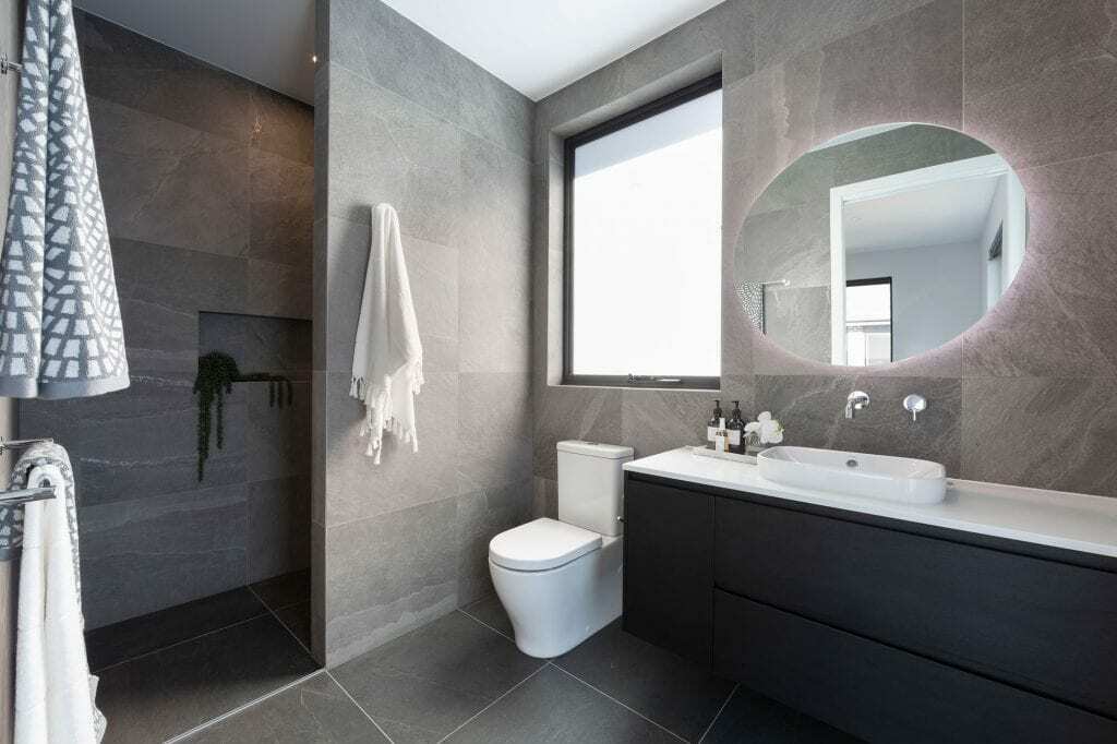 Homes by Howe, knock down rebuild, Red Hill, bathroom, grey slate tiling, inbuilt shower, toilet, black vanity with circular mirror