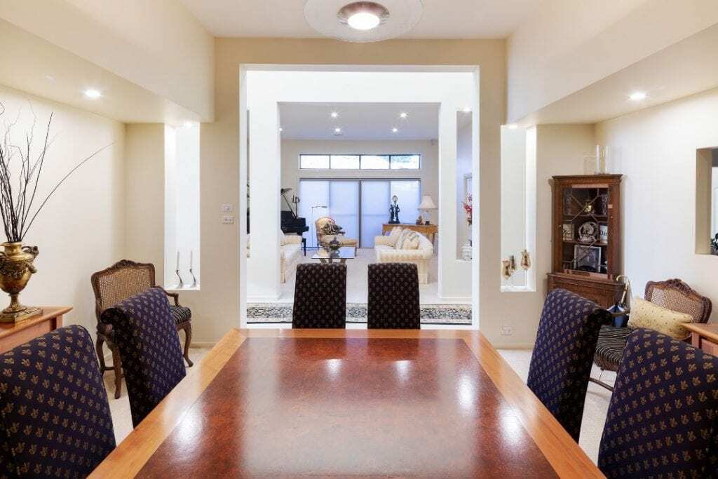 Homes by Howe, renovation, Griffith, dining room, large wooden conference table with high back chairs look through to lounge room