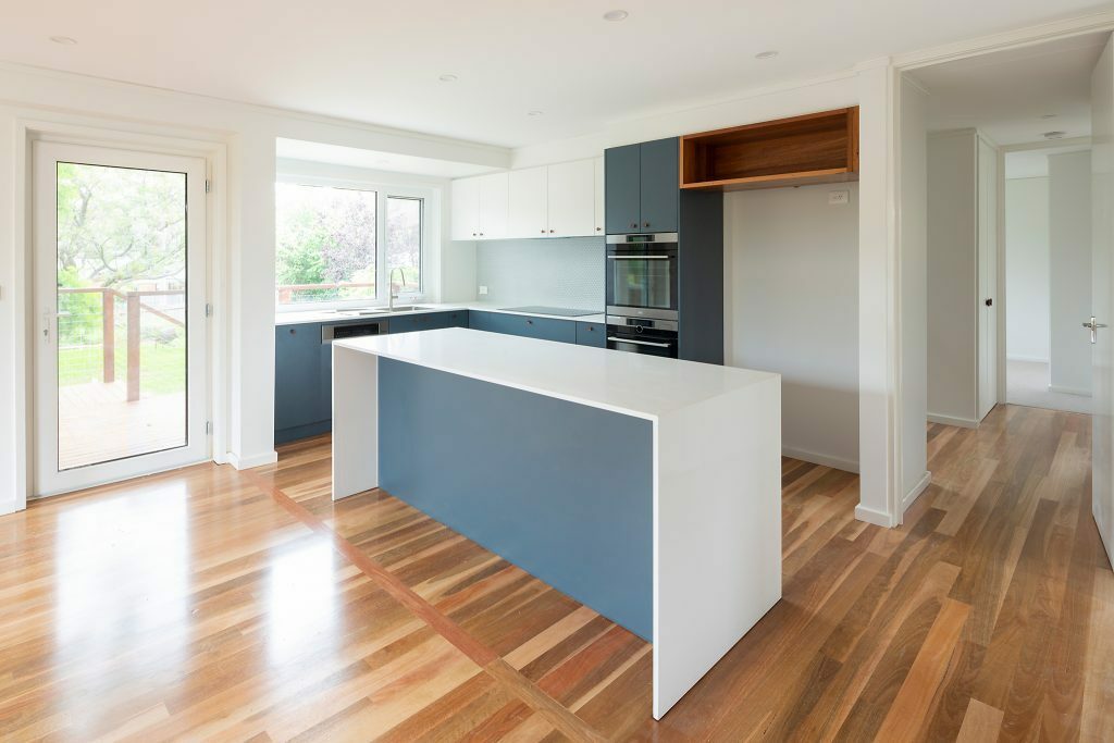 Homes by Howe, renovation, Cook, kitchen, kitchen island with white benchtop, blue highlights and wooden floor boards